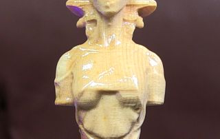 A carved wooden queen chess piece with an Egyptian theme